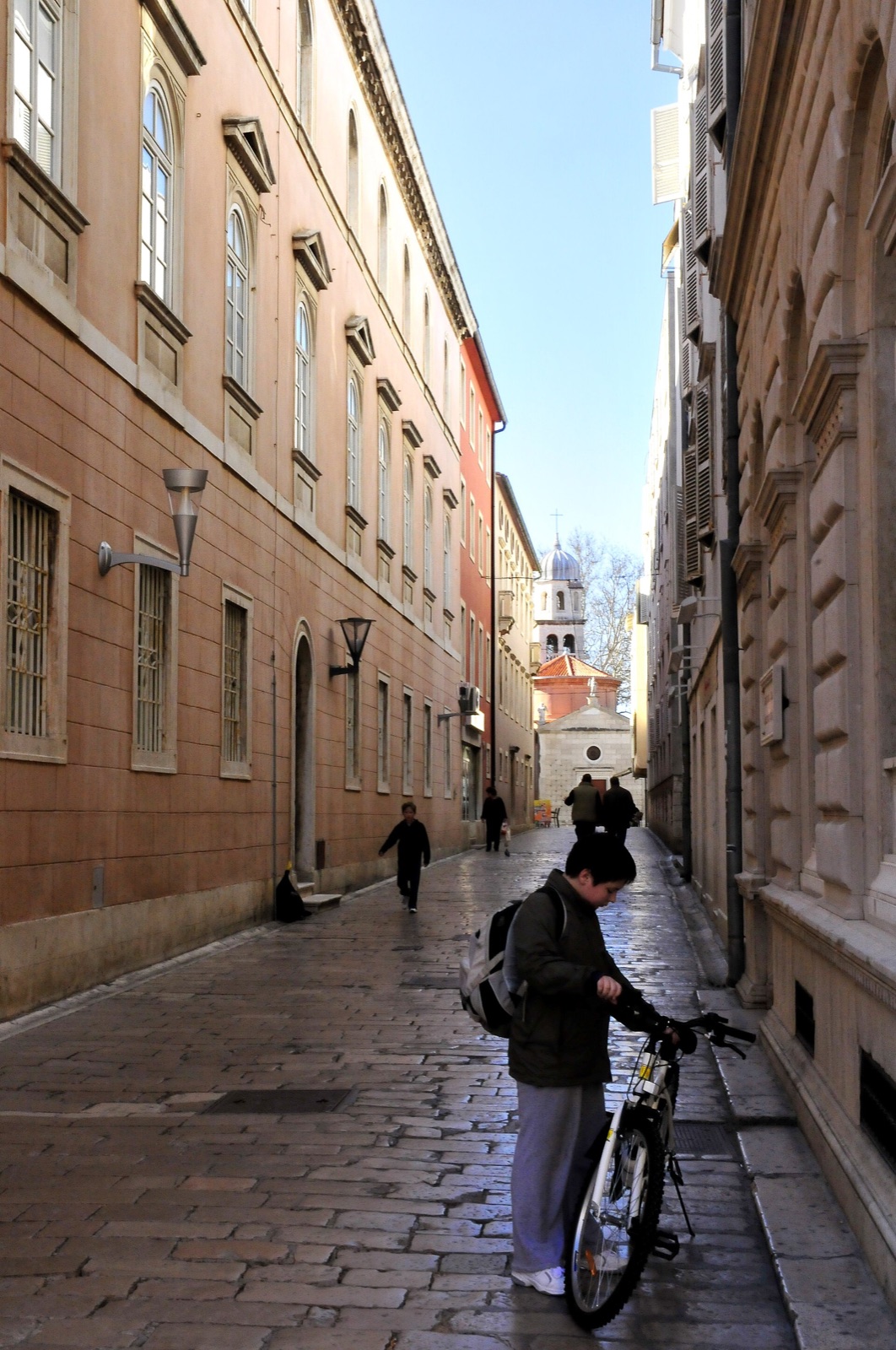 Un ciclista con una bicicleta en una calle histórica en Zadar