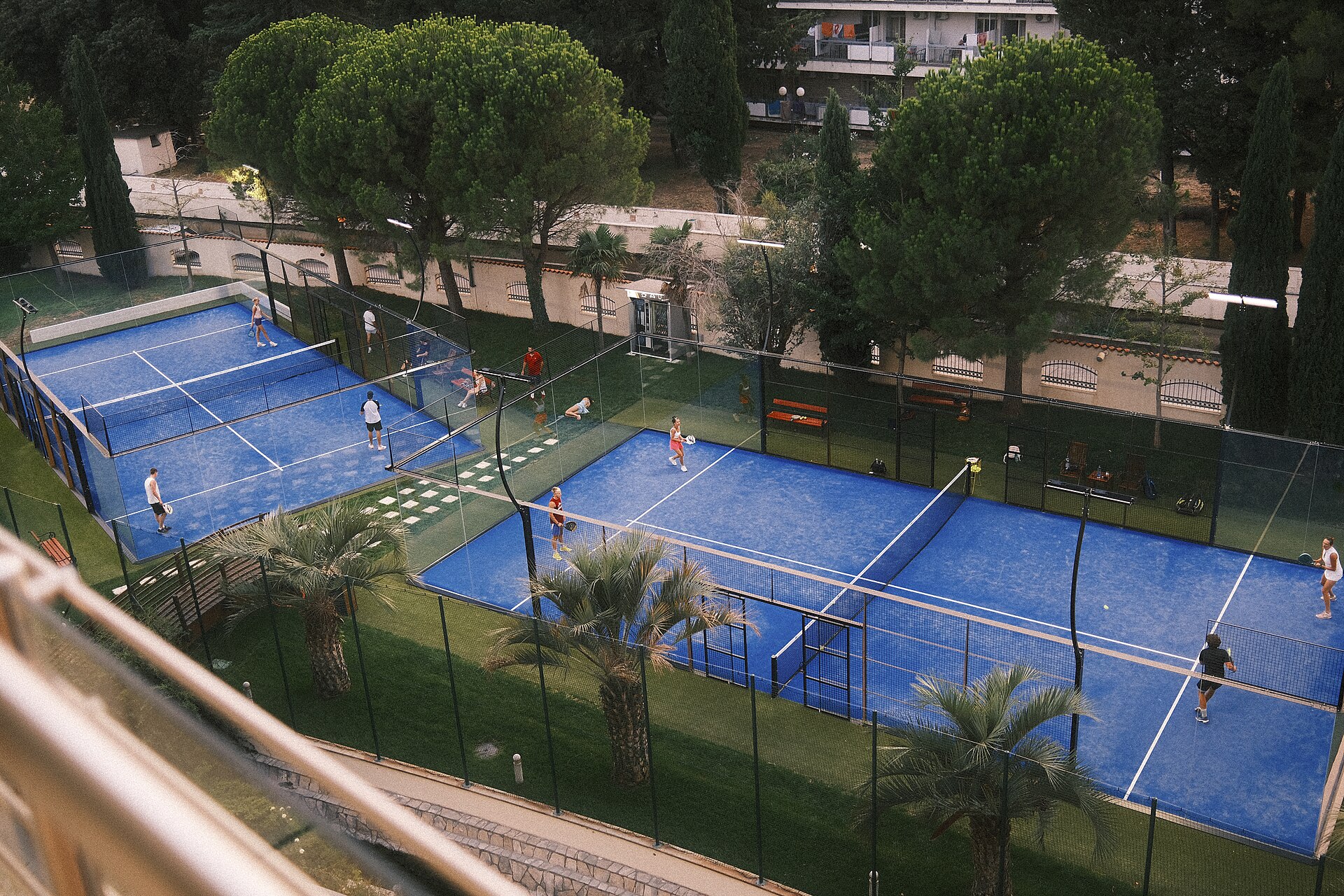 Spillere i en social padelkamp på blå udendørs baner