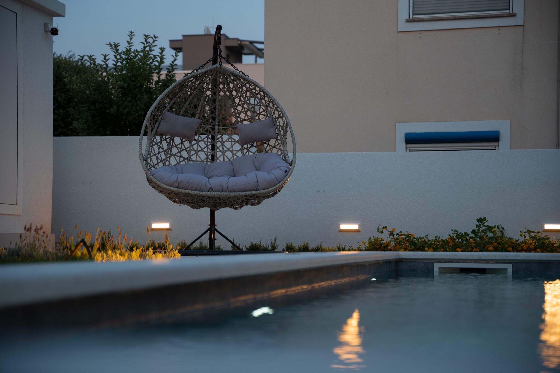 A quiet hanging chair beside the water and garden lights