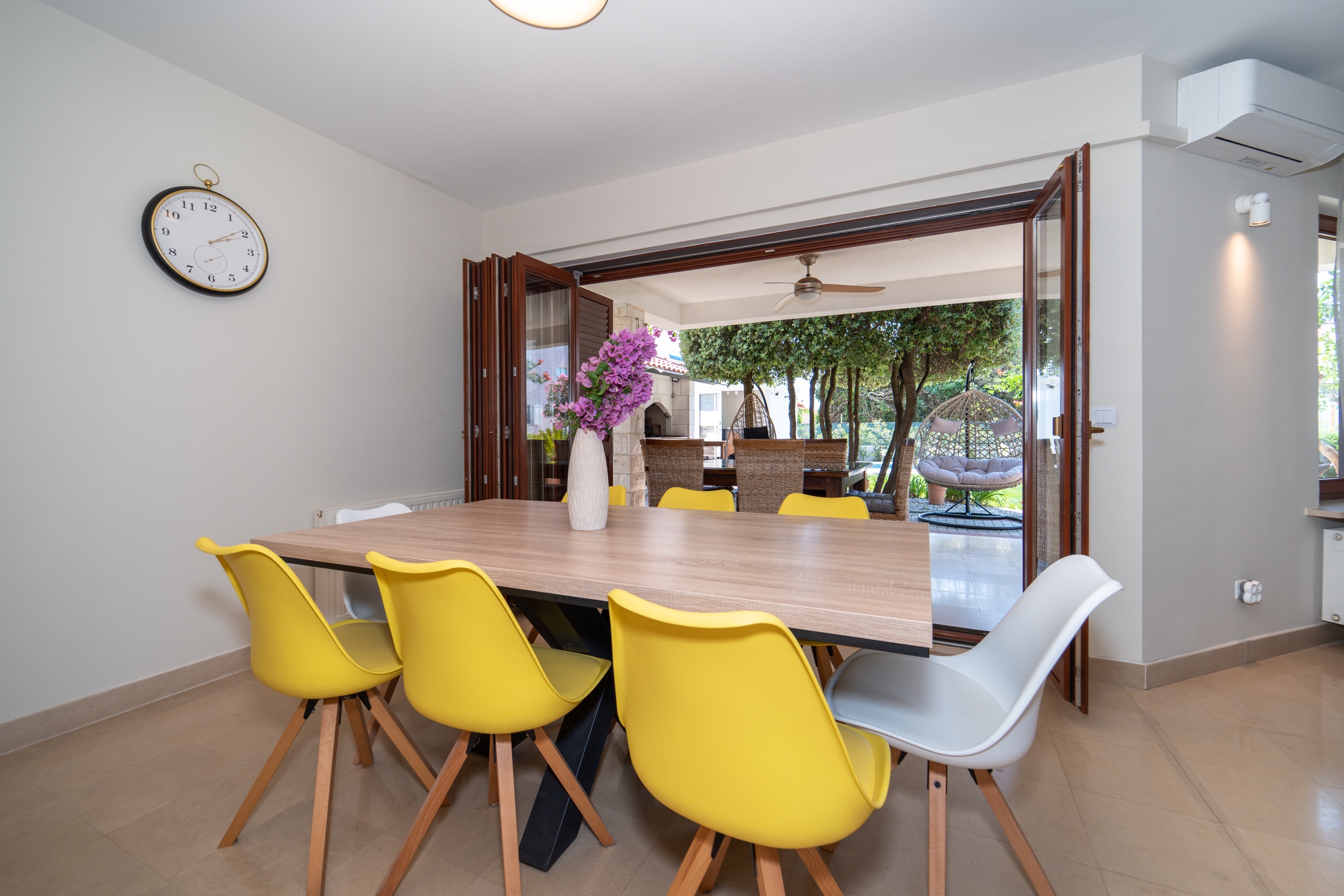 Sala da pranzo interna che si apre completamente sulla terrazza ombreggiata del giardino di Villa Lostura
