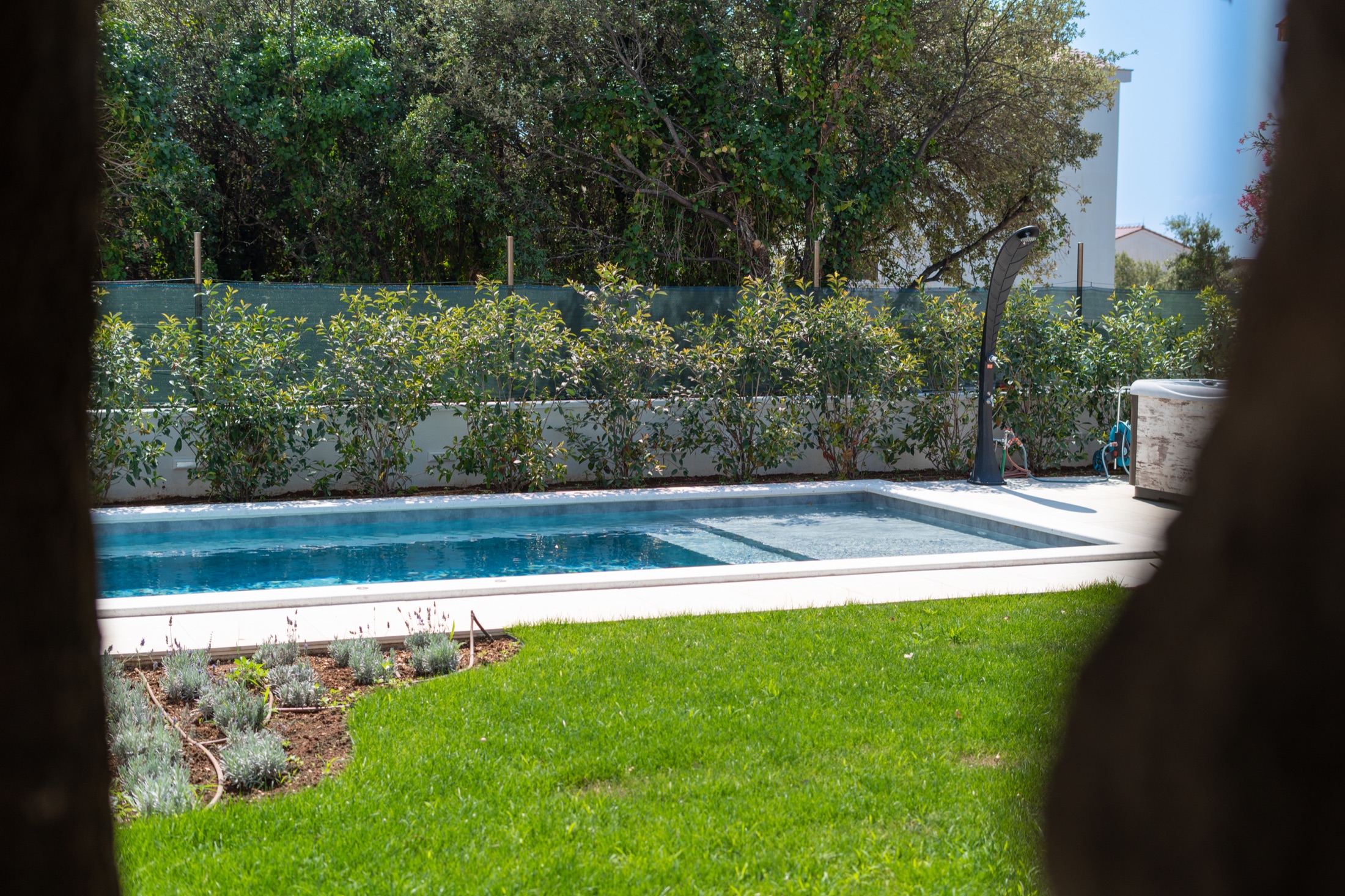 Der private Pool der Villa Lostura, umgeben von Rasen und Grün