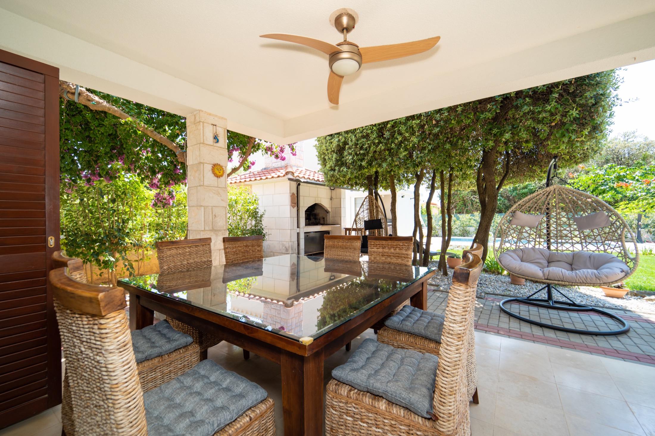 Der Außentisch und der traditionelle Kamin-Grill der Villa Lostura unter mediterranen Bäumen